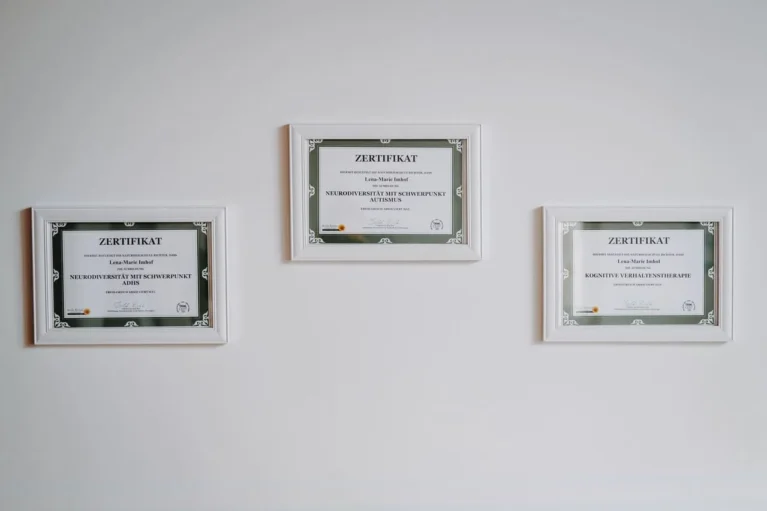 Drei gerahmte Zertifikate an der Wand, die Qualifikationen in Psychotherapie zeigen.