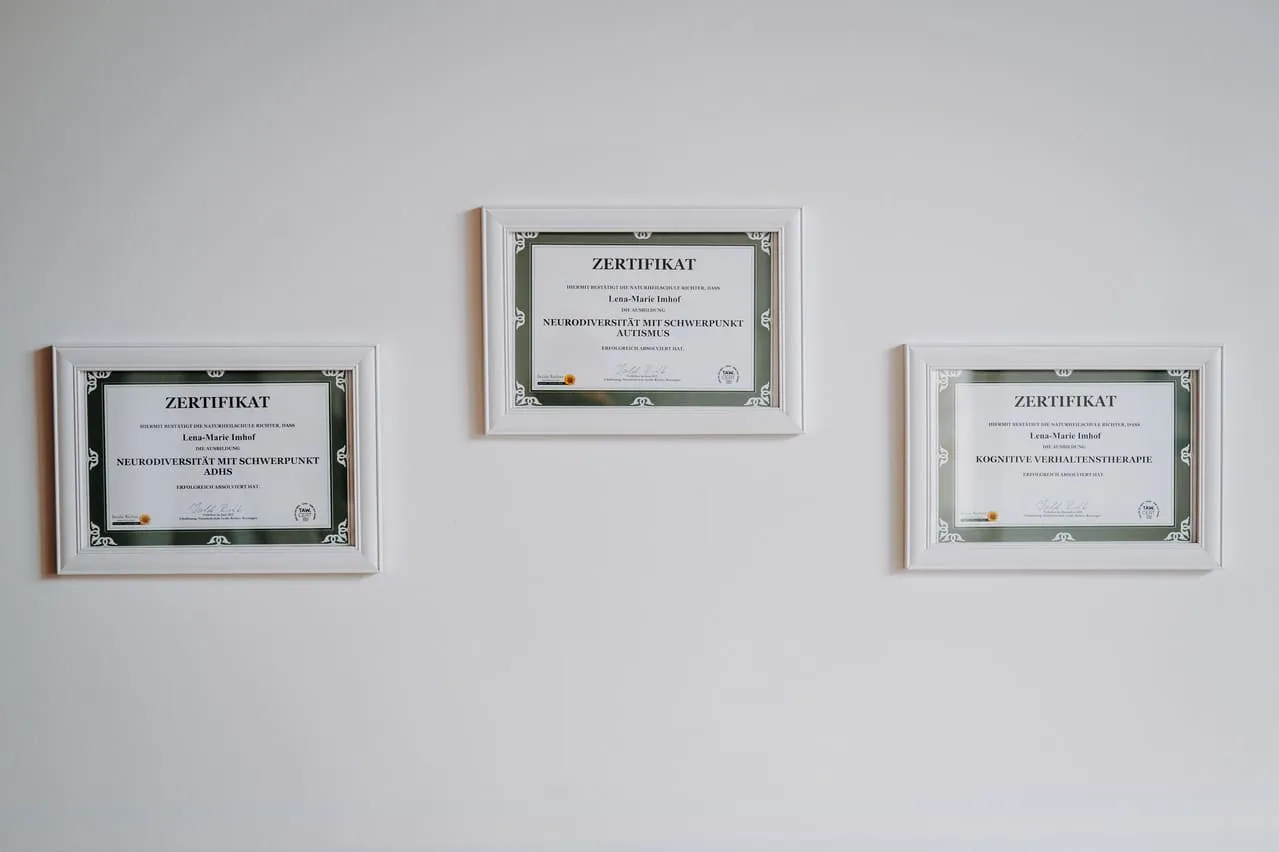 Drei gerahmte Zertifikate an der Wand, die Qualifikationen in Psychotherapie zeigen.