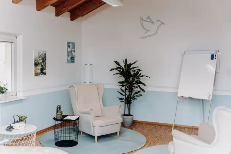 Heller Raum mit gemütlichem Sessel, Pflanzen und Flipchart für psychotherapeutische Sitzungen.