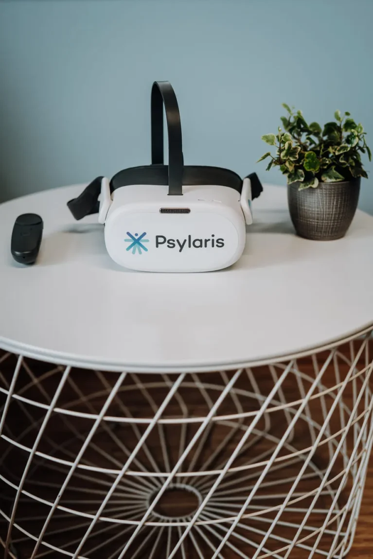 VR-Brille auf rundem Tisch neben kleiner Pflanze, geeignet für Therapieanwendungen.